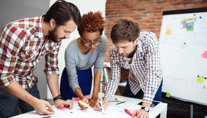 Colleagues speaking, smiling, discussing new ideas at business meeting.